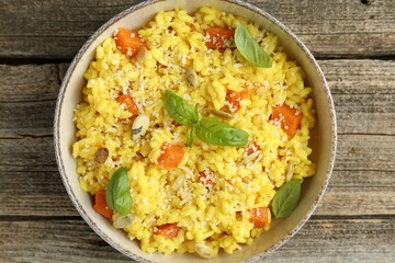 Delicious pumpkin risotto in bowl on wooden table, top view