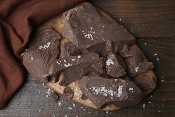 Pieces of chocolate with salt on wooden table, top view