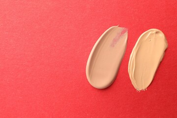 Samples of different foundations on red background, top view. Space for text