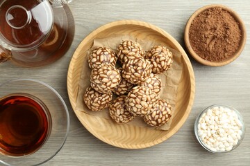 Tasty chocolate puffed rice balls served with tea on wooden table, flat lay