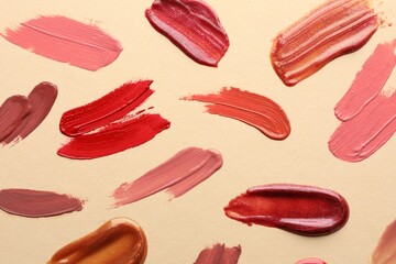 Samples of different lip products on beige background, top view