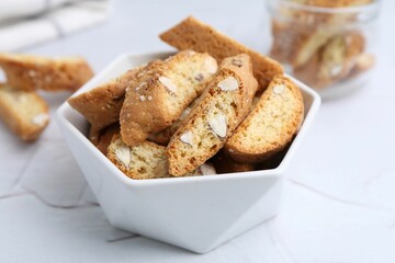 Traditional Italian almond biscuits (Cantucci) in bowl on white table, closeup