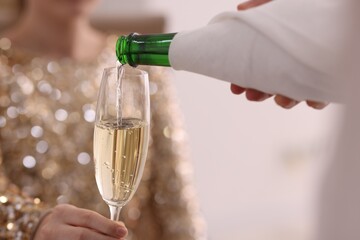 Waiter pouring champagne into woman's glass, closeup