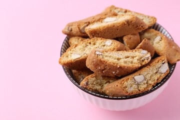 Traditional Italian almond biscuits (Cantucci) in bowl on pink background, closeup. Space for text