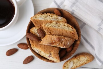 Tasty almond biscuits (Cantuccini), nuts and cup of coffee on white wooden table, flat lay