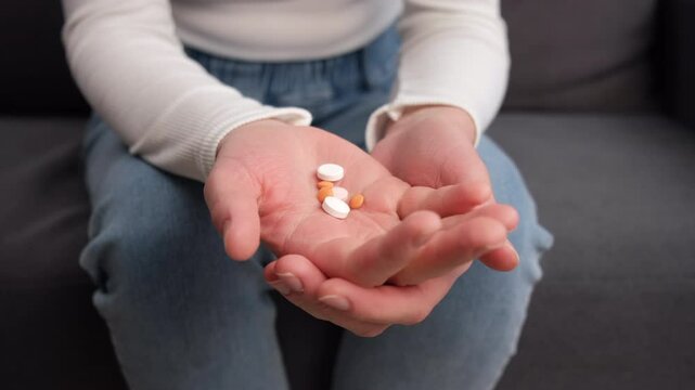 Close up of drug addict  young woman hand holding pills, medicament on sofa at home, abuse overdose. Sick pain of health, unhealthy people. Suicide depressed or despair concept