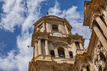 Obraz premium Fragments of majestic facade of Malaga Cathedral (1782), Baroque and Renaissance architecture with grand columns, detailed carvings, and archways under a clear blue sky. Malaga, Andalusia, Spain.