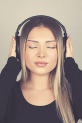 young european woman with blonde hair and headphones listening to music with closed eyes enjoying