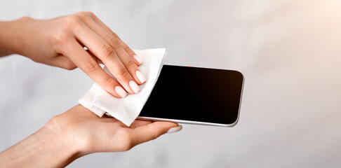 Coronavirus epidemic concept. Girl rubs smartphone antiseptic wipe