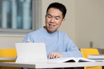 A young student studying with his textbook and tablet