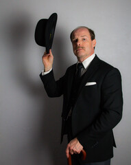 English Gentleman in Dark Suit Politely Doffing Bowler Hat in Somber Manner. Vintage Style of Classic British Businessman.