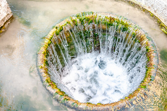 top view, close distance of, a water feature of, cut stone with water cascading into a large, round, open, container