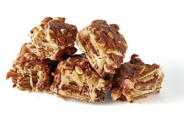 broken pieces of wafer caramel bar covered with nuts and chocolate glaze isolated on white background
