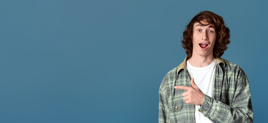 Special offer concept. Excited youth pointing aside on turquoise background, empty space for design. Panorama