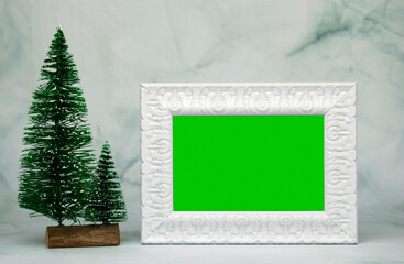 White vintage photo frame with Christmas tree on marble background.Christmas concept.