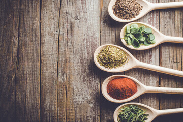 Aromatic herbs and spices on wooden spoons.