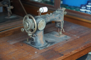 side view antique and dirty black and brown sewing machine on wooden sewing machine table, spool of white thread, object, technology, work, decor, copy space