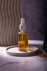 Cosmetic or medical bottle with pipette. Gold liquid product in glass bottle with dropper. Beauty concept.