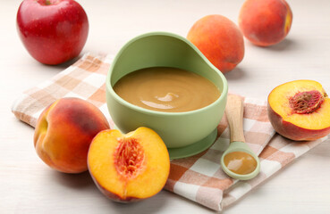 Delicious baby food in bowl and fresh ingredients on white wooden table