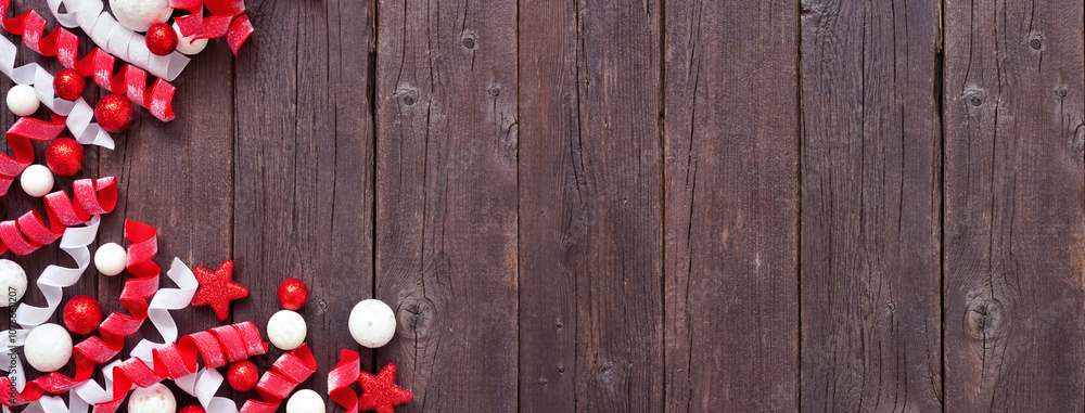 Poster christmas corner border of red and white baubles and curly ribbon. overhead view on a dark wood bann