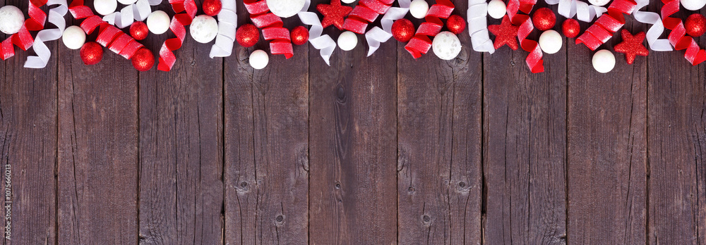 Poster christmas top border of red and white baubles and curly ribbon. above view on a dark wood banner bac