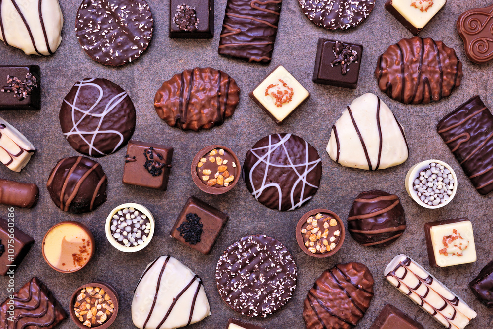 Poster Chocolate background with an assortment of fine, luxurious sweets. Top view on a dark stone background.
