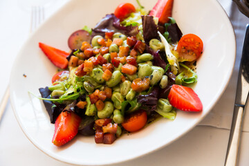 Delicious salad from tender beans with honey soy bacon, greens mix, cherry tomatoes and strawberry..