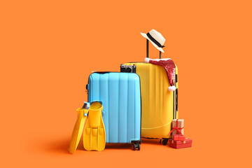 Suitcases with beach accessories, Santa hat and Christmas gifts on color background