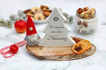 Frohen Nikolaustag. Arrangement mit Süßigkeiten, Nikolausfigur und dem Text wir wünschen einen...