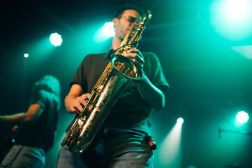 Fototapeta premium Saxophonist performing live on stage with teal lighting