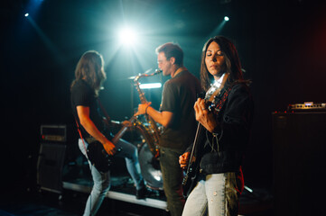 Rock band performing live on stage with saxophone, bass and electric guitar