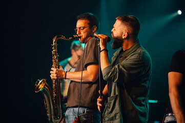 Musicians playing saxophone and singing during live concert