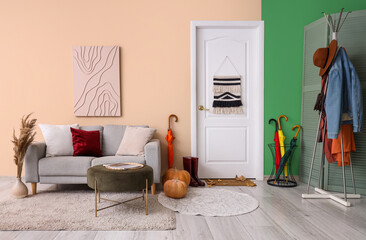 Interior of stylish hallway with door, sofa and umbrellas