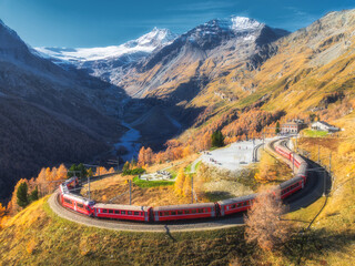 Bernina express train is moving along the swiss alps in autumn
