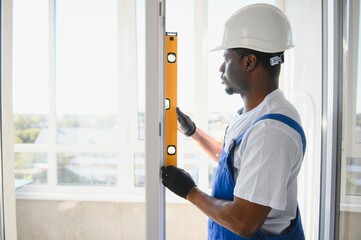 Worker in installing white plastic upvc window on house