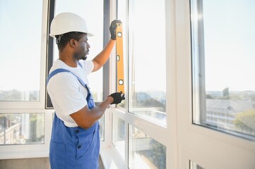 handsome young man installing bay window in new house construction site