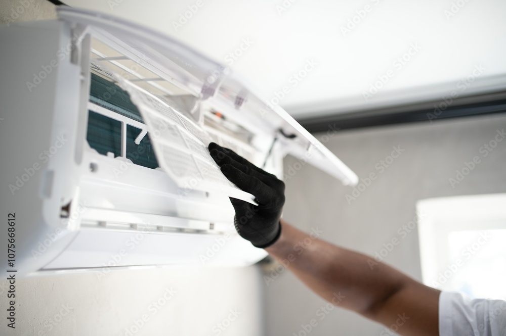 Poster the hands of an african worker insert a new filter into the air conditioner