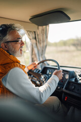 Senior man driving camper van on road trip