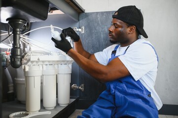 African american plumber change the water filter.
