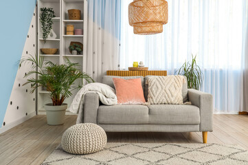 Interior of living room with grey sofa, window and shelf unit