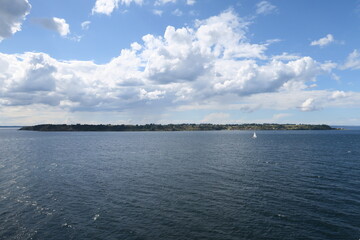 Die Fähre von Kopenhagen nach Oslo fährt an einem sonnigen Sommertag an der schwedischen Insel Ven im Öresund vorbei. Über der Insel türmen sich hohe Wolken.