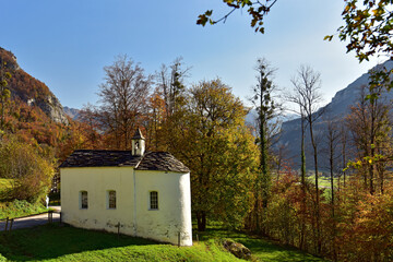 Old traditional swiss chapel in open air museum Ballenberg in autumn. View of the snow-capped Alps. Canton of Bern, Switzerland.