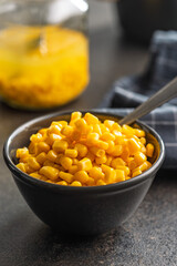 Canned sweet corn in bowl on black kitchen table.