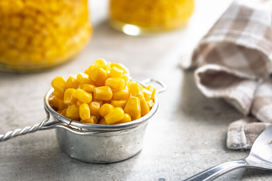 Canned sweet corn in colander on kitchen table.