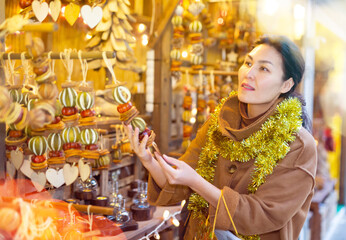 Obraz premium Portrait of happy asian woman choosing Christmas toys at Christmas market