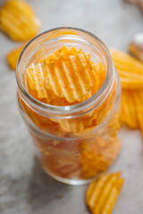 Crispy potato chips in jar on kitchen table.