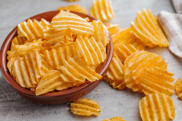 Crispy potato chips in bowl on kitchen table.