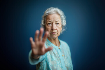 Elderly woman raising her hand in a gesture symbolizing the call to end elder abuse and advocate for the rights and dignity of seniors. Dark blue background.