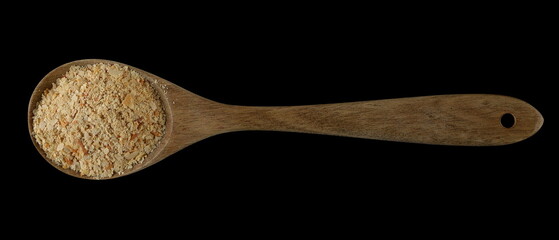 Nutritional yeast pile in wooden spoon (deactivated yeast) isolated on black, top view