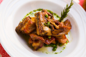 Appetizing baked rabbit meat with garlic served with potatoes on plate